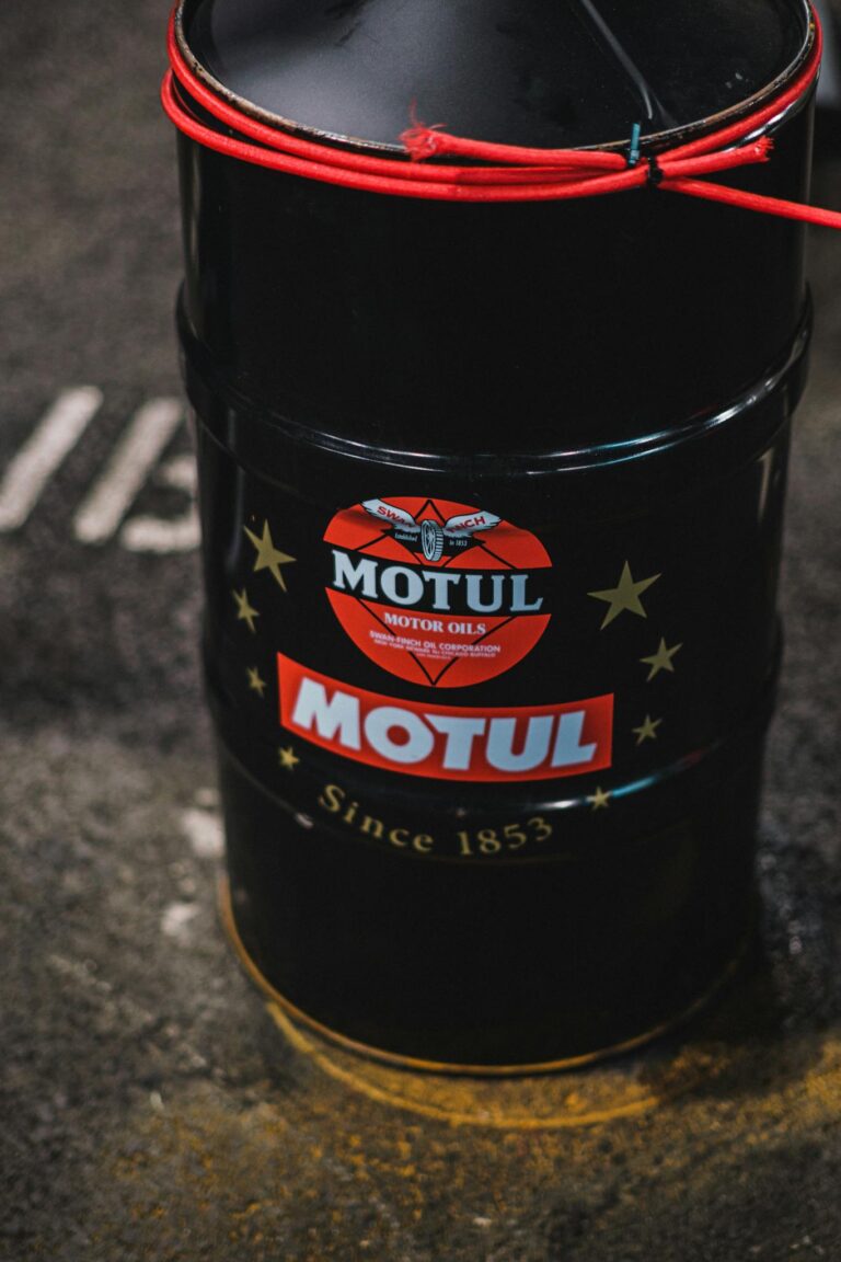 High angle view of Motul oil barrel with logo and text on a garage floor.